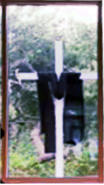 Cross veiled in
			black through window